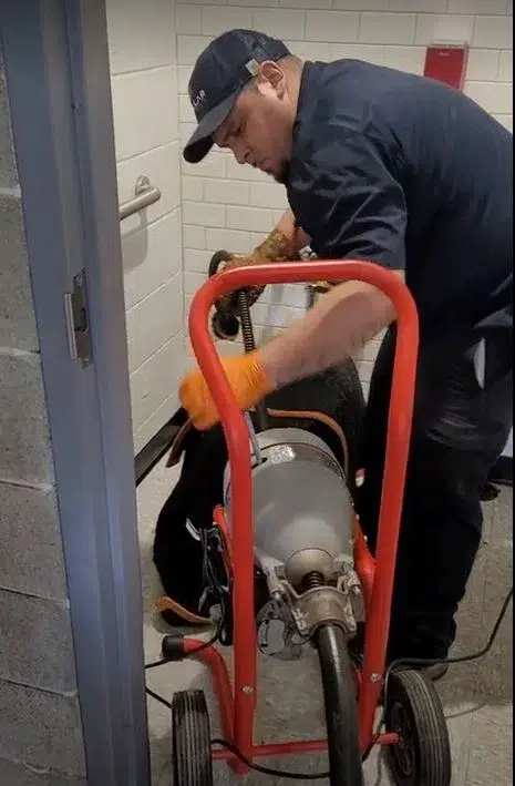 Stellar Plumbing technician using a drain snake machine to clear a clogged toilet in Elk Grove Village, IL