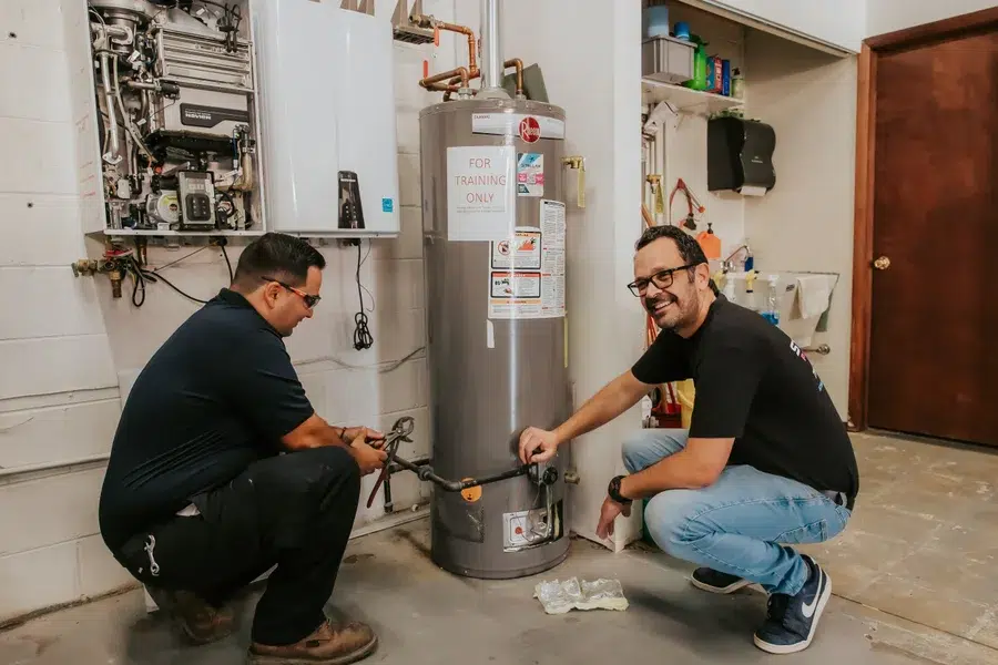 Two Stellar Plumbing technicians servicing a Rheem water heater during training in Elk Grove Village, IL