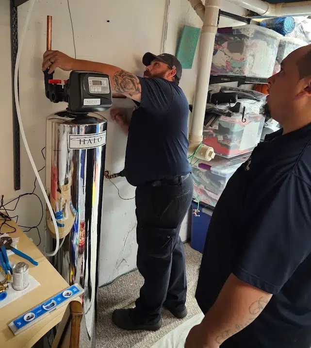 Technician installing water filtration system in residential home