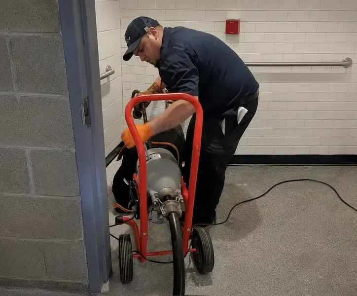 Stellar Plumbing technician using a drain snake machine to clear a clogged toilet in Elk Grove Village, IL