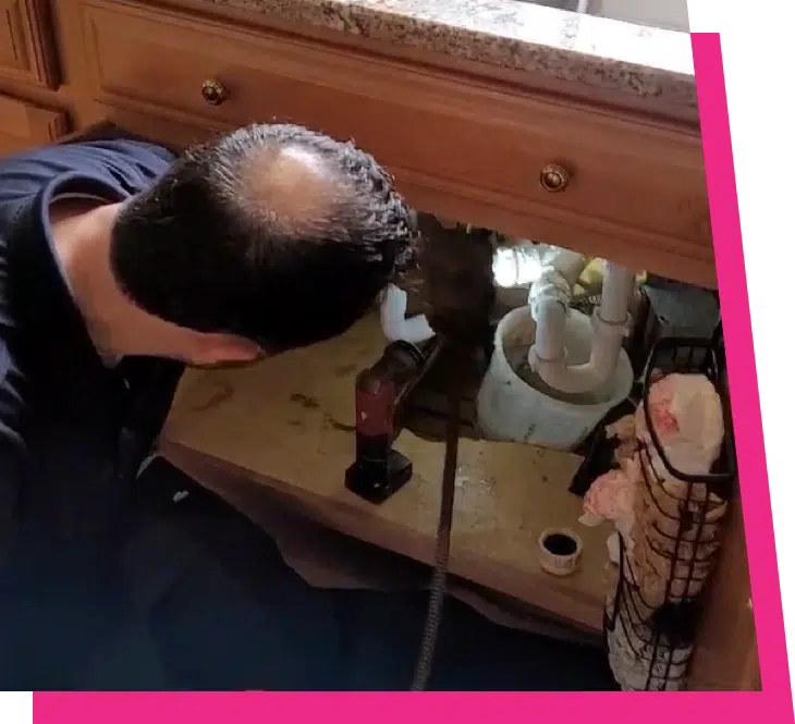 Licensed plumber snaking a clogged kitchen sink drain under the cabinet in Elk Grove Village, IL